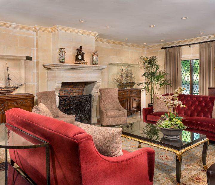 A Large Red Chair In A Living Room Filled With Furniture And A Fireplace