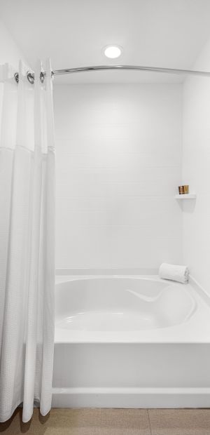 A White Tub Sitting Next To A Shower Curtain