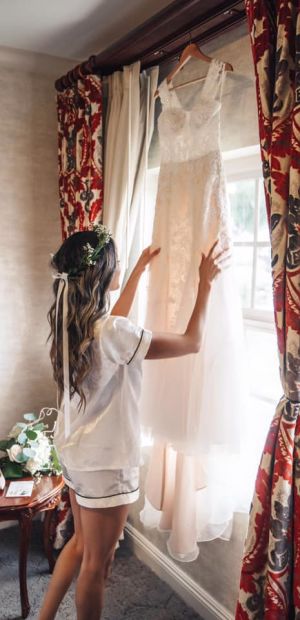 Bride Looking at Her Hanging Wedding Dress