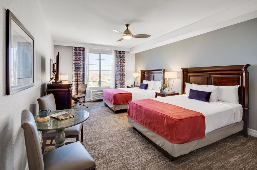 Table, Chairs and two beds with pillows in a 2 Queen Guest Room at Ayres Suites Mission Viejo