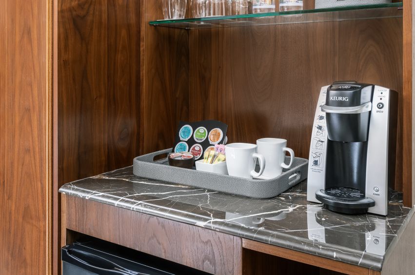 A Counter With A Coffee Maker And Cups On It